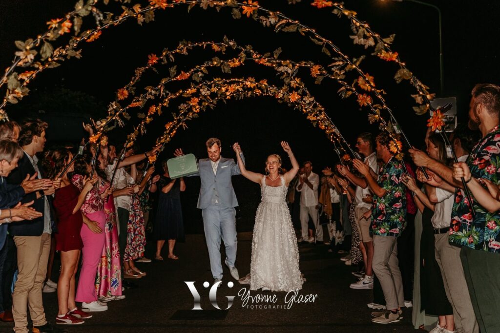bruidspaar s' nachts bij afscheid door lichtjesboog